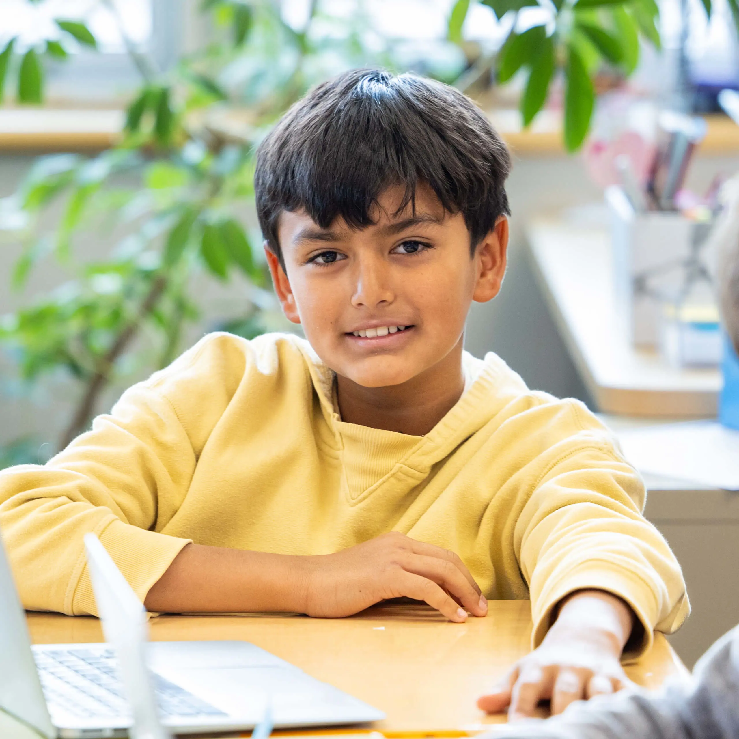 two boys sitting at a table with a computer